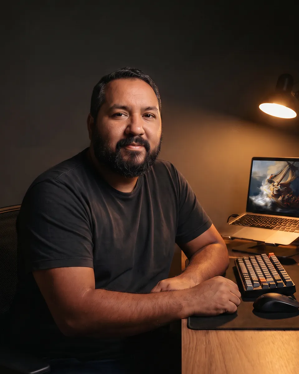 Daniel Pompeu à mesa de trabalho, sob a luz de uma luminária
